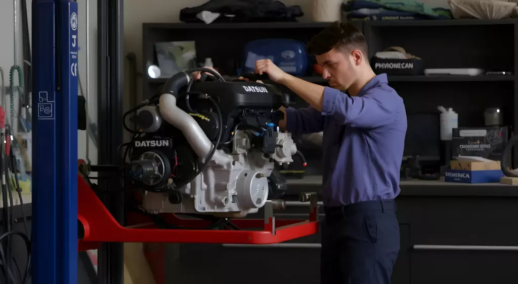 A realistic, high-resolution horizontal photo of a skilled mechanic in a well-lit automotive repair shop, carefully working on a Datsun engine. The scene shows the engine block on a hydraulic lift, surrounded by neatly arranged tools, a toolbox, and a Datsun service manual open on a clipboard. The background features a clean, organized workshop with a workbench, a light fixture, and a subtle hint of a Datsun car chassis in the background. The focus is on the engine and the mechanic’s hands, with a warm, natural lighting that highlights the metallic surfaces and the texture of the engine components.