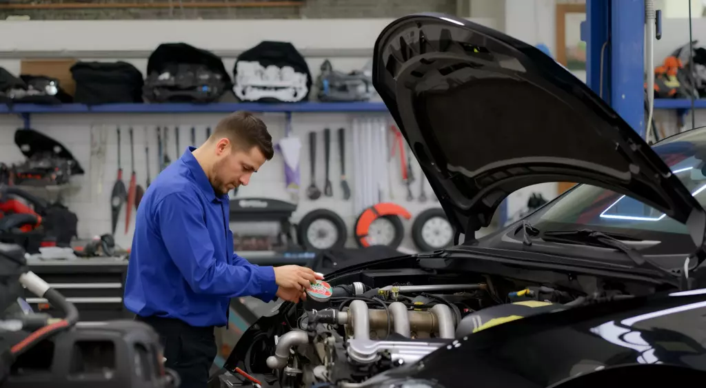 A realistic photo of a professional automotive repair workshop with a mechanic working on a car engine, surrounded by various engine parts and tools, showcasing a clean and organized environment, with a focus on the engine repair process.