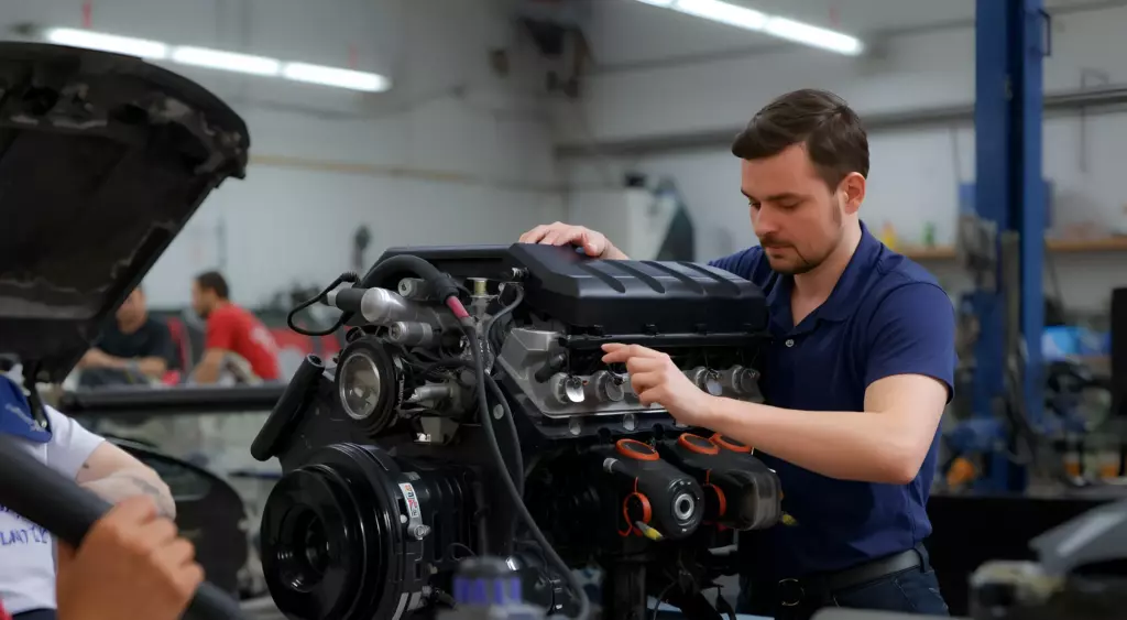 A high-resolution horizontal photo of a skilled mechanic performing a comprehensive overhaul of a Cadillac engine in a well-lit workshop, with tools and engine parts neatly arranged around, showcasing precision and professionalism.