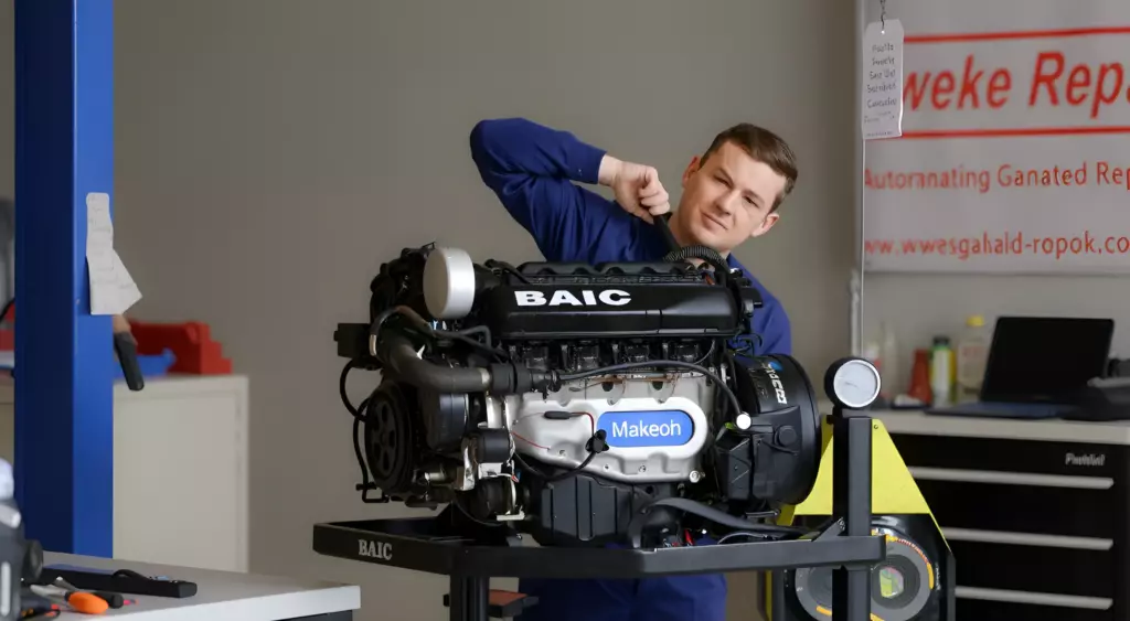 A high-resolution horizontal photo of a professional automotive repair workshop, featuring a technician in blue coveralls working on a BAIC engine mounted on a hydraulic lift. The scene includes a clean workbench with tools, a toolbox, and a diagnostic scanner. The background shows a neatly organized garage with a generic repair sign. The lighting is bright and even, highlighting the engine and the technician's focused expression.